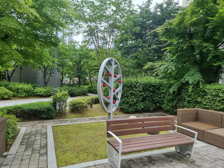 나무 조형물 앞 벤치와 잔디 화단