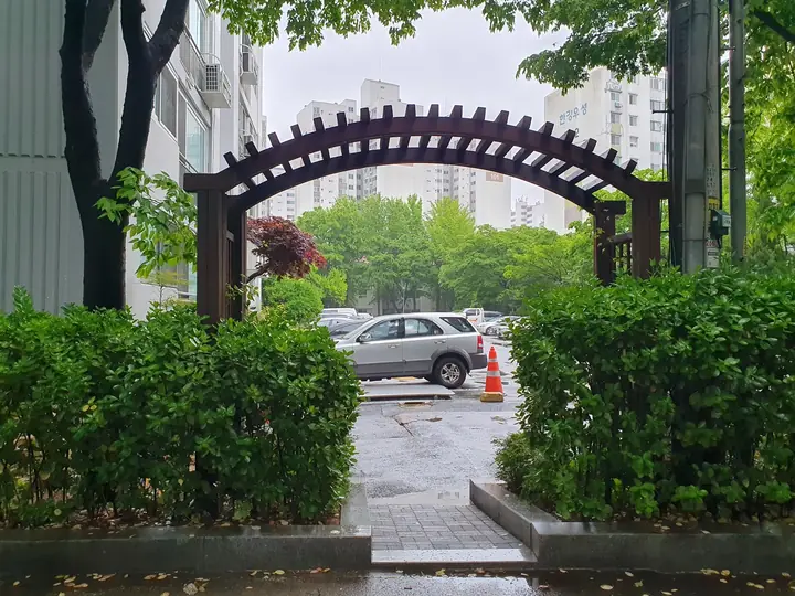 아치 퍼걸러 너머 주차장